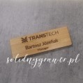 prostokątny identyfikator osobowy wykonany z naturalnego bambusa o wymiarach 75×25 mm. Na powierzchni znajduje się ciemny grawer laserowy przedstawiający dane użytkownika.