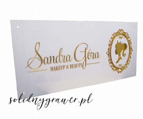 elegancki szyld z plexi w rozmiarze 100x40 cm ze złotymi literami wycinanymi z plexi naklejonymi na białre tło  wykonany przez solidnygrawer.pl dla salonu beauty z logo